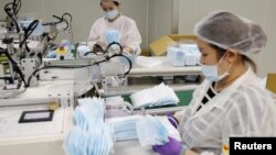 Workers collect surgical masks from a production line in a factory in Taoyuan, Taiwan April 6, 2020. (REUTERS/Ann Wang)