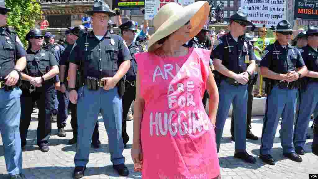 Woman stands in front of police in a shirt reading &quot;Arms are for Hugging&quot; at the Republican National Convention in Cleveland (July 19, 2016).