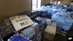 FILE - In this Friday, Feb. 5, 2016 file photo, hundreds of cases of bottled water are stored at a church in Flint, Michigan.