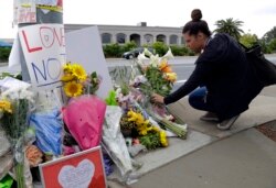 FILE - A woman leaves flowers on a growing memorial across the street from the Chabad of Poway synagogue in Poway, California, Apr. 29, 2019.