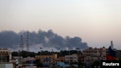 Black smoke rises from the vicinity of the University of Benghazi where clashes are taking place between pro-government forces and Islamist militias in Benghazi, Oct. 18, 2014.