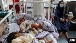 A woman sits next to newborn babies who lost their mothers following a suicide attack in a maternity hospital, in Kabul, Afghanistan, May 13, 2020.