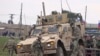 In this frame grab from video, people and soldiers gathering next to an American military convoy stuck in the village of Khirbet Ammu, east of Qamishli city, Syria, Feb. 12, 2020. 