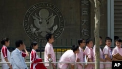 FILE - In this May 2012 photo, Chinese students wait outside the U.S. Embassy for their visa application interviews in Beijing. China's government is protesting the U.S. treatment of Chinese students arriving to study in America, saying some have been interrogated and deported.