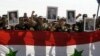 A handout picture released by the official Syrian Arab News Agency (SANA) shows soldiers from the Syrian government forces holding the Syrian flag and pictures of President Bashar al-Assad and his late father Hafez al-Assad, August 1, 2012.