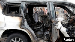 FILE - An Afghan journalist films a damaged vehicle at the site of a blast in Kabul, Afghanistan, Dec. 20, 2020. 
