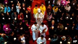 FILE - A bishop, center, accompanied by other clergy members, walks down the aisle during mass at the Cathedral of the Immaculate Conception, a government-sanctioned Catholic church, in Beijing, China, March 31, 2018. 