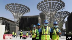 FILE - In this Oct. 8, 2019, file photo, technicians walk at the under construction site of the Expo 2020 in Dubai, United Arab Emirates. (AP Photo/Kamran Jebreili, File)