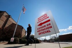 FILE - A sign points potential voters to an official polling location during early voting in Dallas, Feb. 26, 2020.