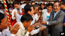 Cambodian Prime Minister Hun Sen, right, greets villagers as he arrives for an inauguration ceremony of a road funded by Japan for its official use at Kdey Takoy village, outside of Phnom Penh, Cambodia, Tuesday, March 13, 2018. (AP Photo/Heng Sinith)