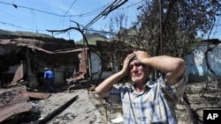 An ethnic Uzbek holds his head in his hands as he stands beside the wreckage of his burned out home in Osh, 14 June 2010