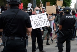 A participant in a protest over the death of George Floyd, a handcuffed black man in police custody in Minneapolis, squares off with Denver police officers, May 29, 2020, in Denver.