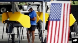 រូបឯកសារ៖ ពលរដ្ឋអាមេរិកាំងម្នាក់ដែលពាក់ម៉ាស់ ចូលរួមបោះឆ្នោតក្នុងក្រុង Santa Clarita នៅរដ្ឋ California កាលពីថ្ងៃទី ១២ ខែឧសភា ឆ្នាំ២០២០។