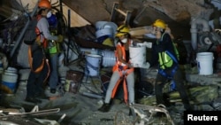 Members of rescue teams remove debris in the rubble of a collapsed building after an earthquake in Mexico City, Sept. 24, 2017. 