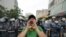 FILE - A protester wearing a scarf of the Shi'ite Hezbollah movement chants slogans while being watched by Lebanese police during an anti-U.S. rally near the United States' embassy building in Awkar, northeast of Lebanon's capital Beirut, July 10, 2020.