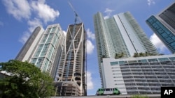 A high-rise building under construction is shown next to high-rise condominium buildings, Sept. 7, 2017, in downtown Miami.