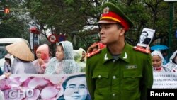 Seorang polisi berjaga di depan para pendukung pengacara Le Quoc Quan, yang berdemo di luar pengadilan di Hanoi (18/2).