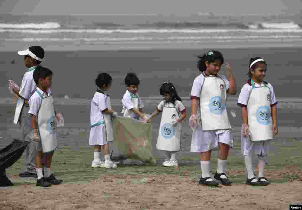 Anak-anak sekolah mengumpulkan sampah di Pantai Clifton, Karachi, Pakistan, sebagai bagian peringatan Hari Bumi. (Reuters/Akhtar Soomro)