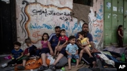 Palestinska porodica sjedi vani nakon što im je kuća pogođena u izraelskim zračnim napadima, grad Gaza, 17. maj 2021.