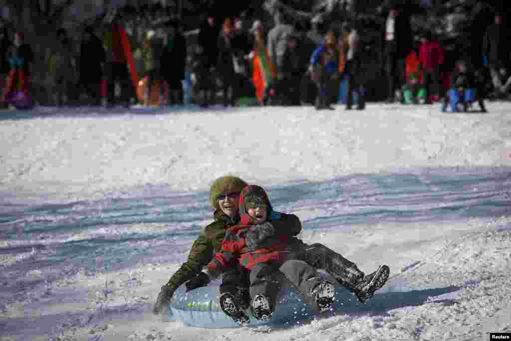 People ride a sled down Cedar Hill in Central Park in New York City, Jan, 3, 2014.