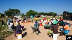 FILE - Women and children wait for their turn to fetch water in a poor suburb of Harare, Zimbabwe, March, 31, 2020.