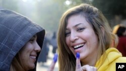 Warga Mesir menunjukkan tanda di jarinya seusai memberikan suara dalam pemilu referendum konstitusi baru di sebuah TPS di Kairo, Mesir, Sabtu (15/12). 