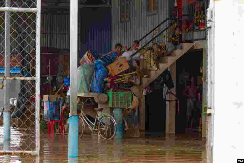 កុមារមួយក្រុមអង្គុយលើជណ្តើរផ្ទះដែលត្រូវបានទឹកជន់លិច នៅសង្កាត់ស្ពានថ្ម ខណ្ឌដង្កោរ ភ្នំពេញ ថ្ងៃទី១៤ ខែតុលា ឆ្នាំ២០២០។ (ទុំ ម្លិះ/វីអូអេ)