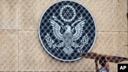 A worker carries cardboard inside the compound of the United States embassy in Havana, Cuba, Sept. 29, 2017. 