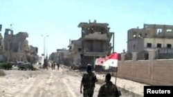 Dalam foto yang dirilis Kantor Berita Suriah (SANA) ini, nampak pasukan setia Presiden Bashar al-Assad membawa bendera nasional mereka saat melintasi jalanan di kota Qusair (5/6).