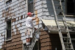 A worker for Viking Painting coats the exterior of a house, June 5, 2020, in Euclid, Ohio. U.S. unemployment dropped unexpectedly in May to 13.3% as reopened businesses began recalling millions of workers faster than economists had predicted.