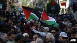 Des Palestiniens agitent des drapeaux nationaux, marchAnt dans les rues de la ville occupée de Ramallah, en Cisjordanie, appelant à la cessation des divisions entre le Fatah et le Hamas, à l'unification de la Cisjordanie et de la bande de Gaza, le 12 janvier 2019 (AFP/A. MOMANI)