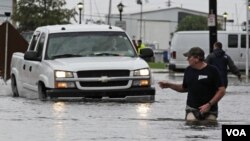 Seorang laki-laki memberi petunjuk jalan bagi pengendara truk melintasi banjir akibat badai tropis Lee di New Orleans (3/9).
