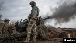 Ukrainian service members fire a howitzer M119 at a front line near Bakhmut