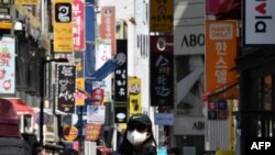 A woman wearing a face mask walks through a shopping district in Seoul, South Korea, on April 23, 2020.