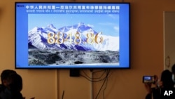 Nepalese government officers watch a live telecast of a joint announcement on the height of Mount Everest, in Kathmandu, Nepal, Dec. 8, 2020.