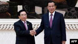 រូបថតដែលចេញផ្សាយដោយទូរទស្សន៍ជាតិកម្ពុជានៅថ្ងៃទី២៩ ខែវិច្ឆិកា ឆ្នាំ២០២១ បង្ហាញពីនាយករដ្ឋមន្ត្រីឡាវលោក Phankham Viphavanh (ឆ្វេង) ចាប់រលាក់ដៃ​ជាមួយនាយករដ្ឋមន្ត្រីកម្ពុជាលោក ហ៊ុន សែន នៅវិមាន​សន្តិភាព​ក្នុង​រាជធានី​ភ្នំពេញ។ (រូបថត​ដោយ An Khoun SamAun/ទូរទស្សន៍​ជាតិ​កម្ពុជា (ទទក)/AFP)