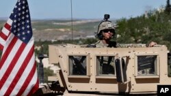 FILE - A U.S. soldier sits on his armored vehicle on a road in Manbij, Syria, April 4, 2018.
