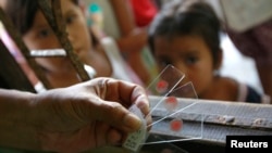 រូបថតឯកសារ៖ មន្ត្រី​ក្រសួង​សុខភាព​សាធារណៈថៃ កាន់​សំណាក​ឈាម​ដែល​បាន​ធ្វើ​តេស្តទៅ​លើ​កុមារ​ដែល​រស់​នៅ​តាម​ព្រំដែន​ថៃ​-មីយ៉ាន់ម៉ា នៅ​ឯ​ក្លីនិក​ព្យាបាល​ជំងឺ​គ្រុន​ចាញ់​ក្នុង​ខេត្ត Kanchanaburi ប្រទេស​ថៃ កាលពីថ្ងៃទី​២៦ ខែ​តុលា ឆ្នាំ២០១២។