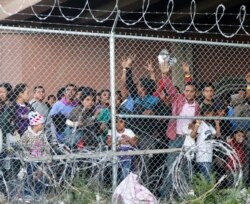 FILE - Central American migrants wait for food in a pen erected by U.S. Customs and Border Protection to process a surge of migrant families and unaccompanied minors in El Paso, Texas, March 27, 2019.
