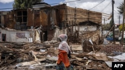 አንዲት ሴት፣ ከፍተኛ ፈረሳ በተካሄደበት የአዲስ አበባ ታሪካዊው ፒያሳ ሰፈር መሃል ስታልፍ - መጋቢት 14፣ 2024