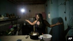 FILE- Dugleidi Salcedo complains to a neighbor about the high price of food as she prepares arepas for her three sons in her kitchen in the Petare slum, in Caracas, Venezuela, Feb. 14, 2019. 