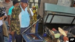 An armed police officer stands guard over the bodies of six attackers who were killed as they tried to gain entry into a military barracks on the coast, in Mombasa, Kenya, Nov. 2, 2014.