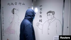 湖北省武汉市雷神山医院一名工作人员走过中国国家主席习近平戴着口罩的素描海报。该医院于2020年初武汉爆发Covid-19新冠疫情后火速建成。