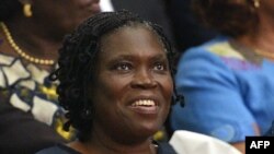 Simone Gbagbo, Ivory Coast's former first lady, smiles as she sits in the dock at the Court of Justice in Abidjan on Dec. 26, 2014 for the start of her trial.