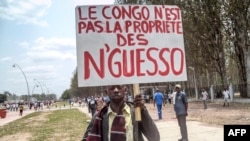 Seorang pria membawa plakat bertuliskan "Kongo bukan milik Nguesso," dalam demonstrasi melawan Presiden Denis Sassou Nguesso di Brazzaville, Republik Kongo (27/9). (AFP/Laudes Martial Mbon)