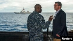 U.S. Secretary of Defense Ash Carter (R) speaks with U.S. Navy Cmdr. Robert C. Francis Jr., as Carter and Malaysian Defense Minister Hishammuddin Hussein (not pictured) visited the USS Theodore Roosevelt aircraft carrier in the South China Sea, in this handout image, Nov. 5, 2015.