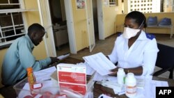 A patient waits for his pills as he meets with a nurse at Nhlangano health center in Swaziland, Oct. 28, 2009. 