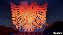 FILE - A man types in front of the logo of the "Kosova Hacker's Security" in this photo illustration taken in Sarajevo, Bosnia and Herzegovina, Oct. 16, 2015. 