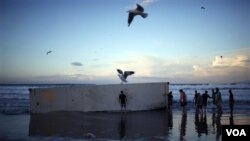 Warga berusaha mengosongkan kontainer yang terhempas di pantai Mount Maunganui. Kontainer ini berasal dari kapal Rena yang karam sejak 13 Oktober yang lalu (16/10).
