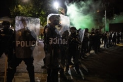 Tear gas fills the air as police make a line of control during protests, Sept. 18, 2020, in Portland, Ore.